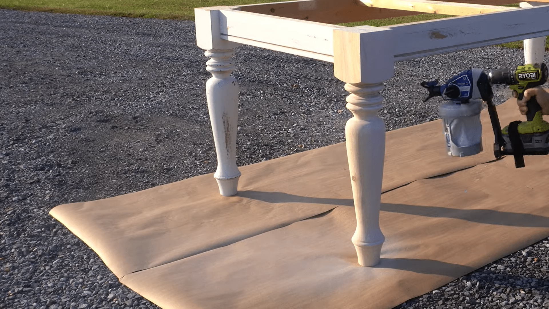 a person spray painting wooden table legs outdoors while refinishing a farmhouse style table frame