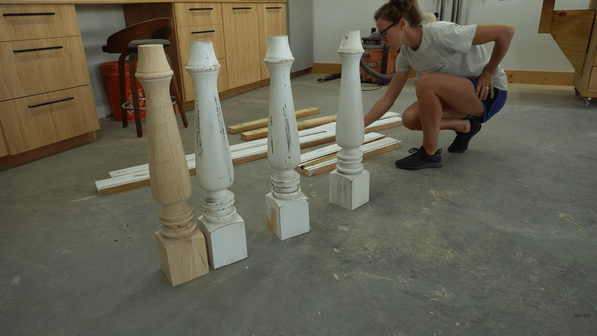a woman examining turned wooden table legs and measuring wood pieces on a workshop floor during furniture assembly