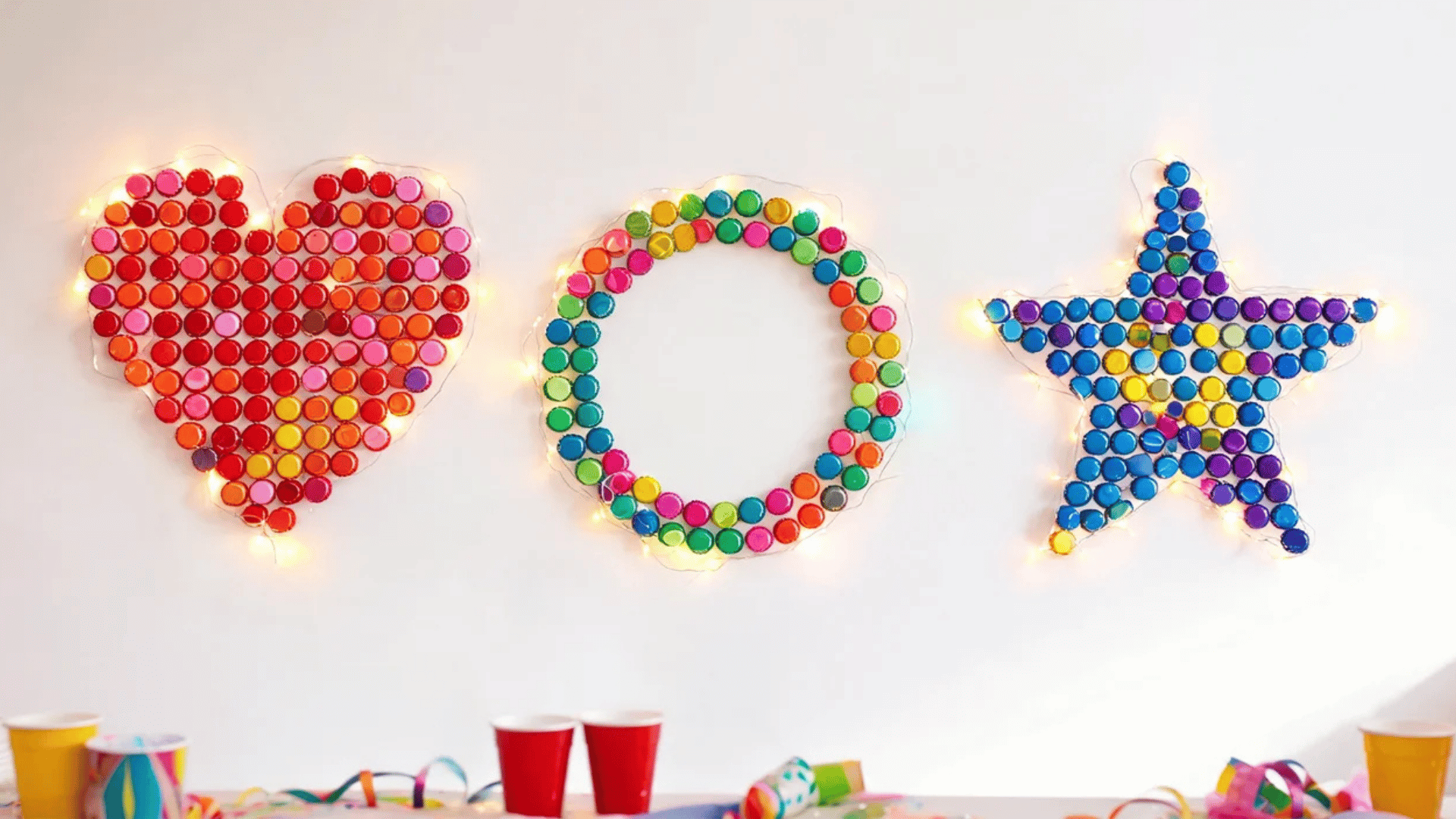 colorful dots arranged as heart circle and star shapes on wall with small glowing lights around each shape