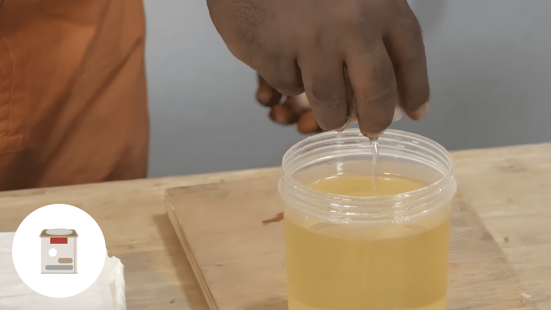 hand pouring liquid polish from container onto cloth preparing solution for how to polish wood furniture with careful application