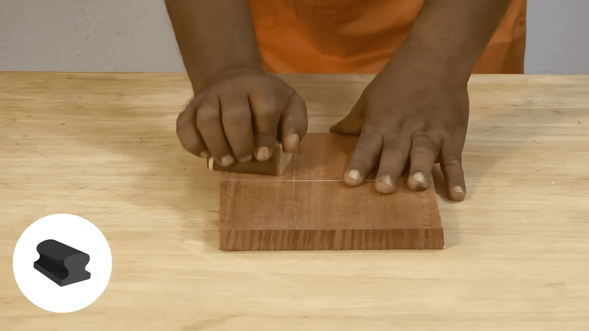 hands sanding small wooden block on table demonstrating how to polish wood furniture with steady motion and care