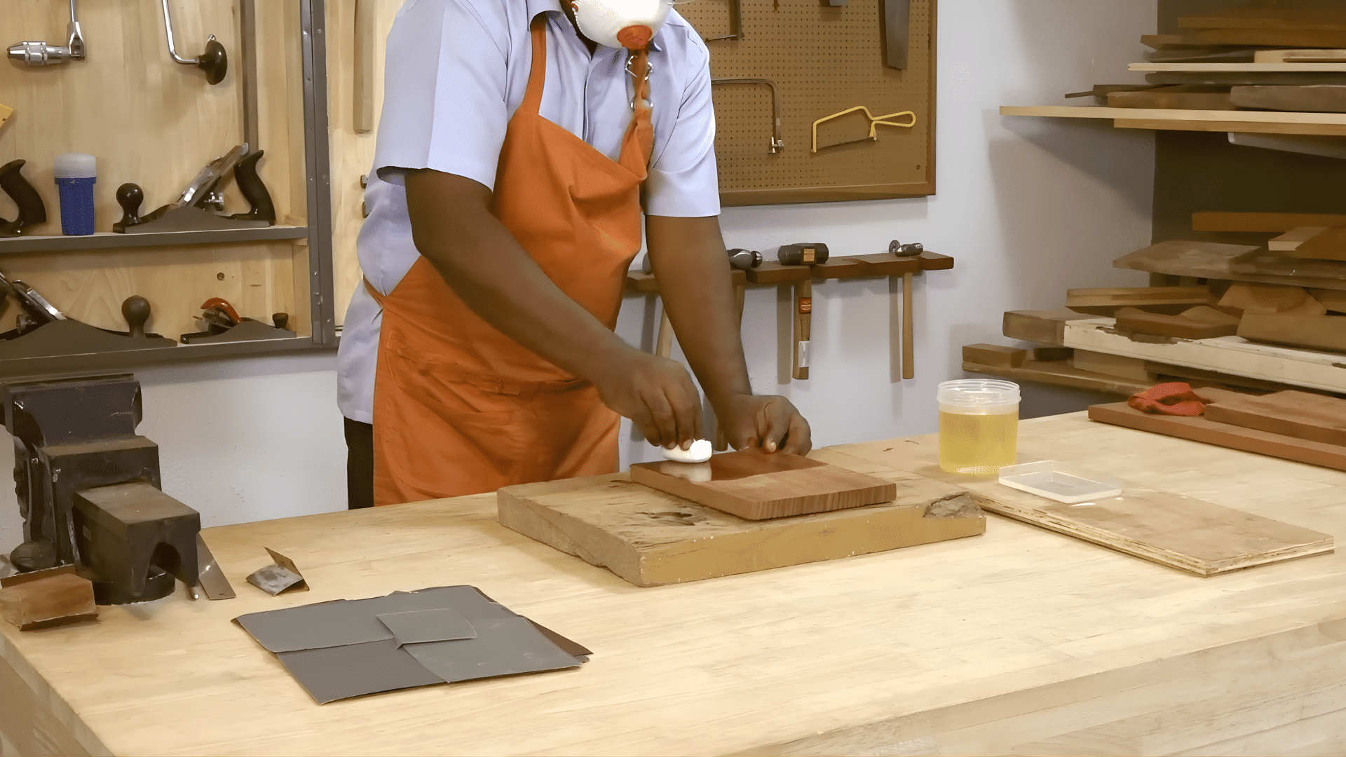 person wearing apron rubbing polish onto wooden surface with cloth demonstrating how to polish wood furniture