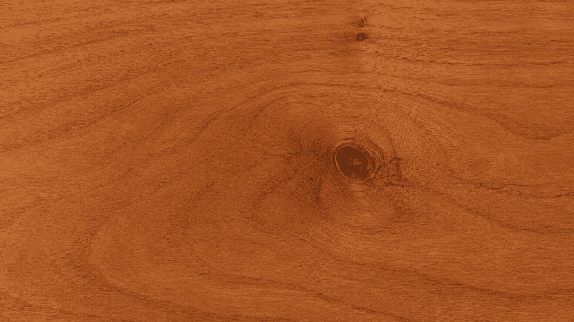 warm brown wood surface with smooth flowing grain patterns and a dark knot near the center right area