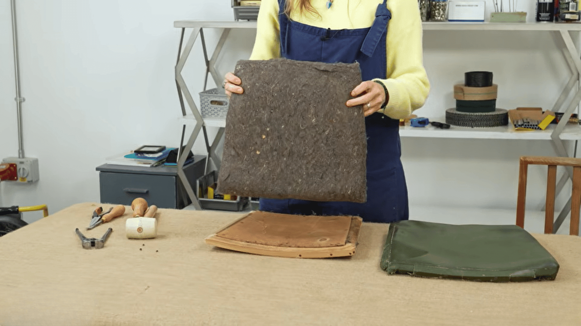 woman holding chair cushion foam to reupholster dining chairs in workshop