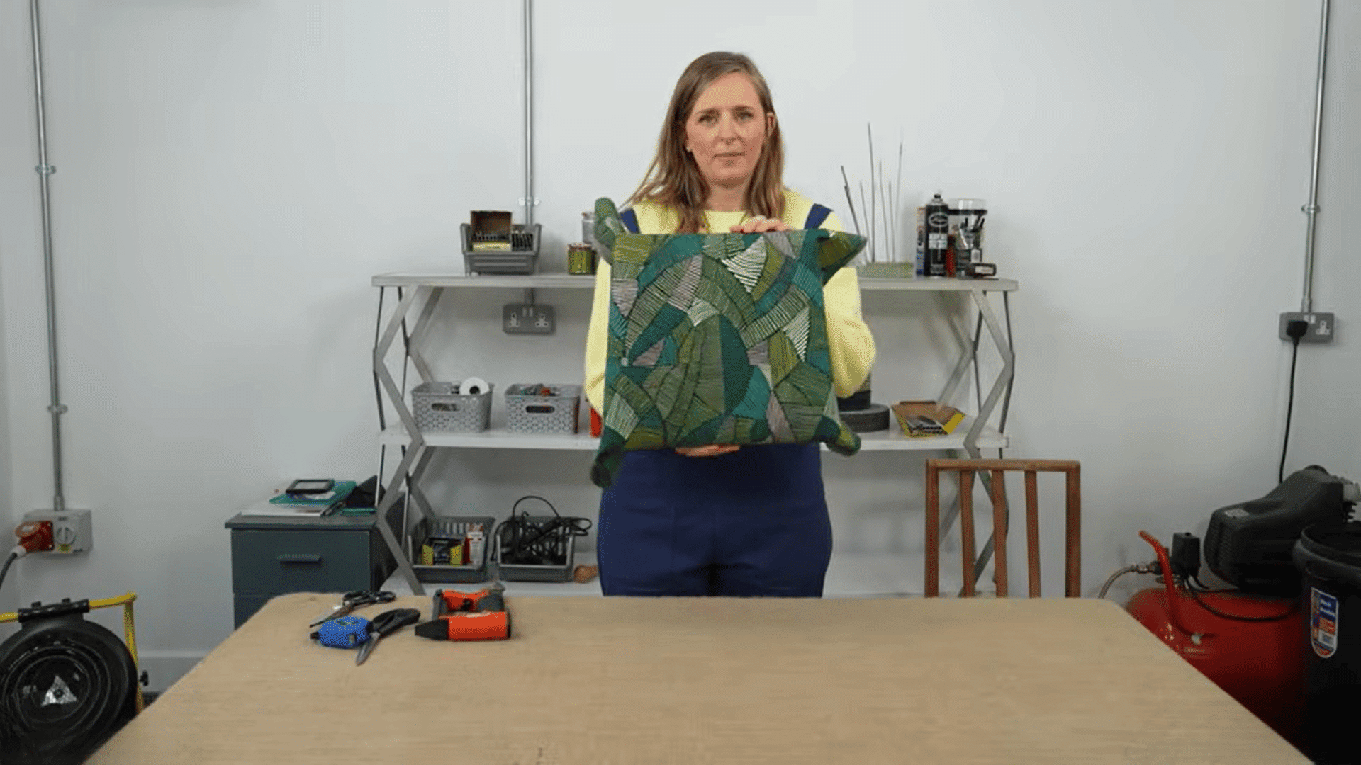 woman showing finished cushion after reupholster dining chairs in workshop