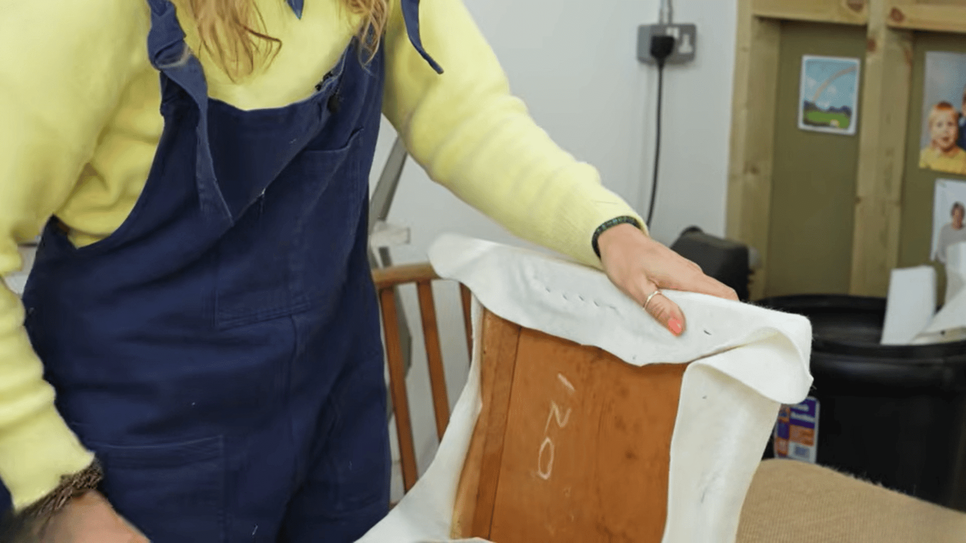 woman stapling fabric padding to reupholster dining chairs in workshop