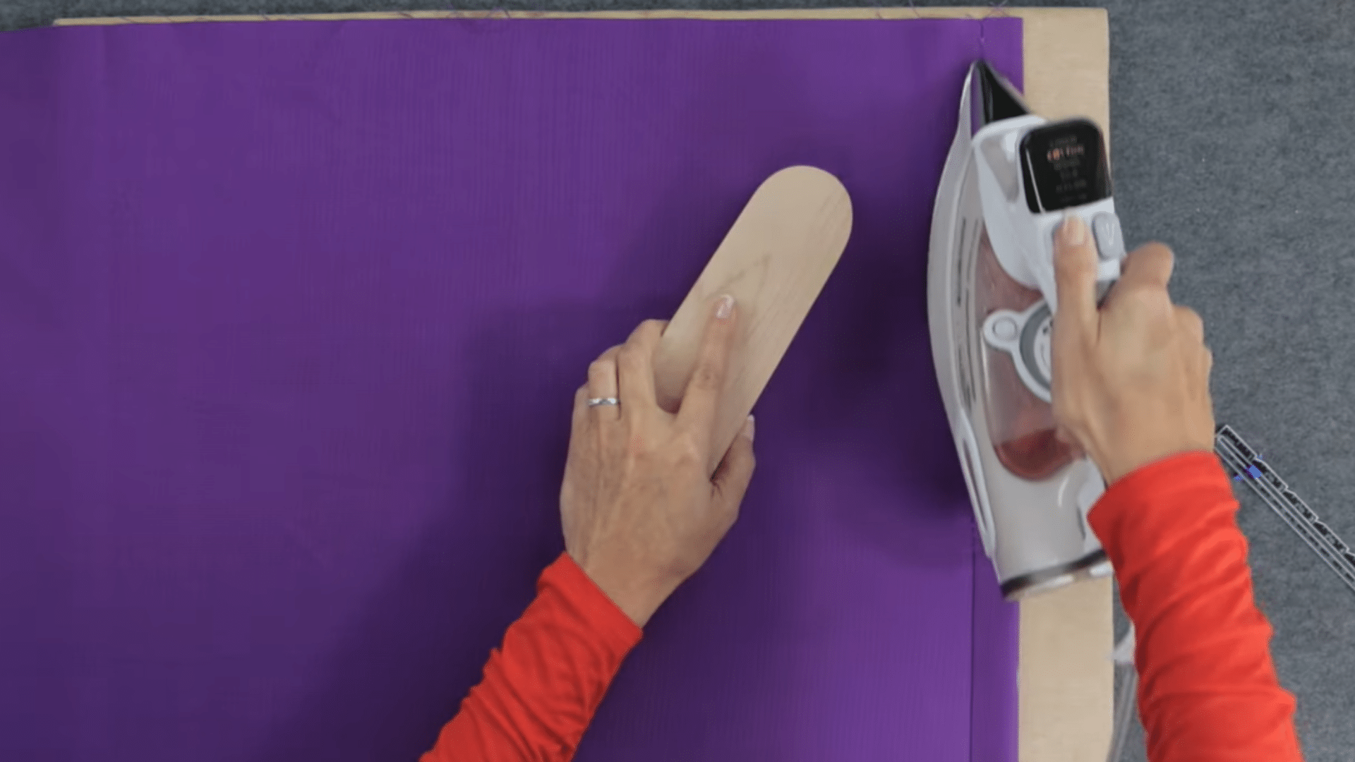 fabric laid flat with edges being aligned and pressed using an iron to prepare material before cutting and sewing curtains