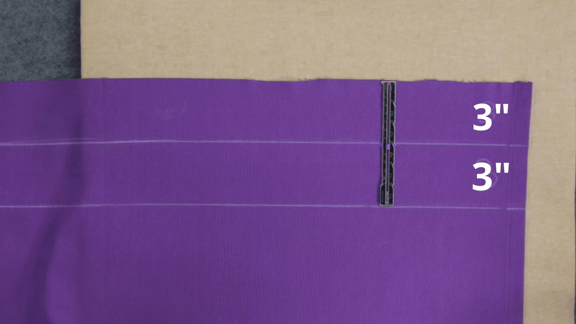 fabric marked with chalk at three inch intervals and aligned with ruler to prepare even bottom hem before folding and stitching