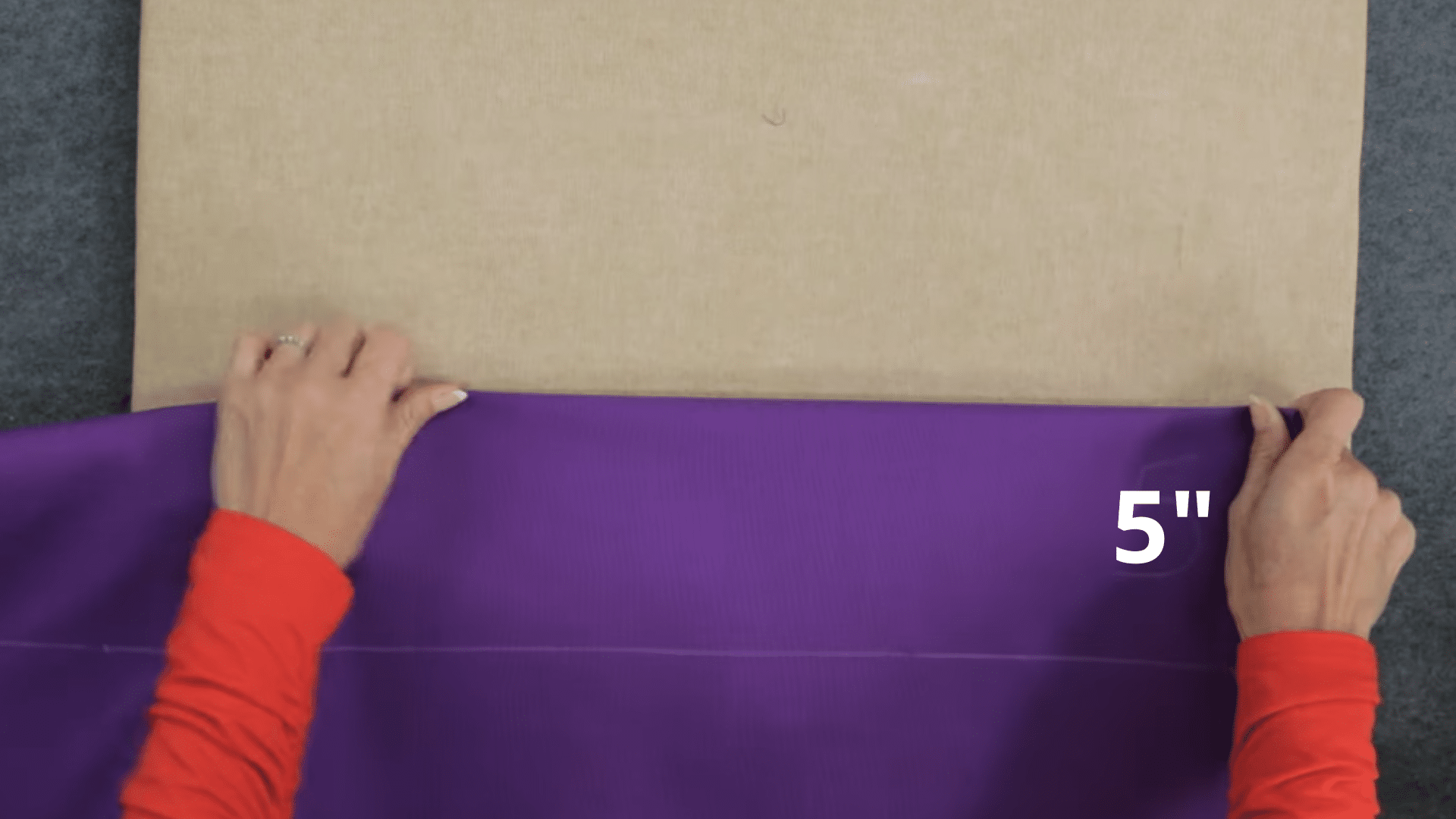 hands folding curtain fabric at the top edge with five inch measurement marked to create a strong header section