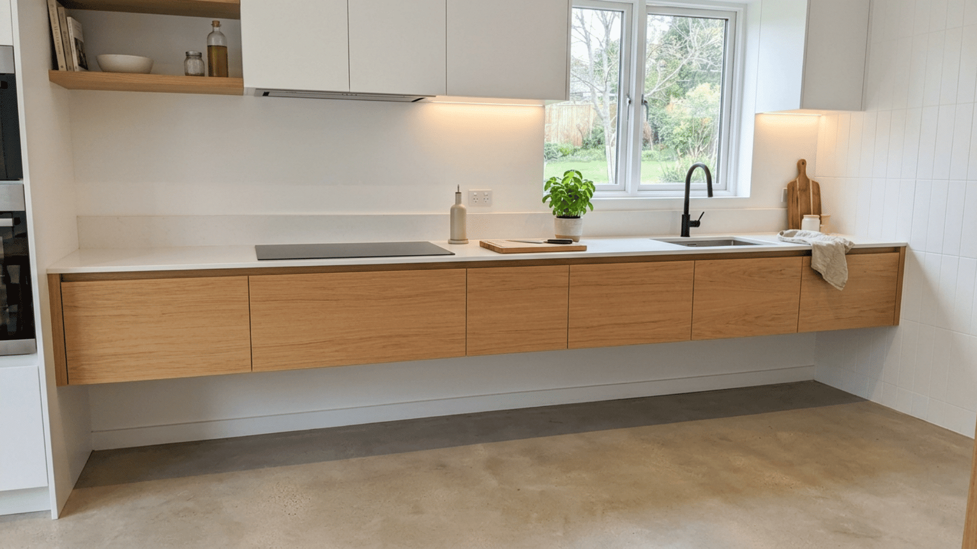 minimal kitchen with floating wood lower cabinets white counters black faucet window and concrete floor