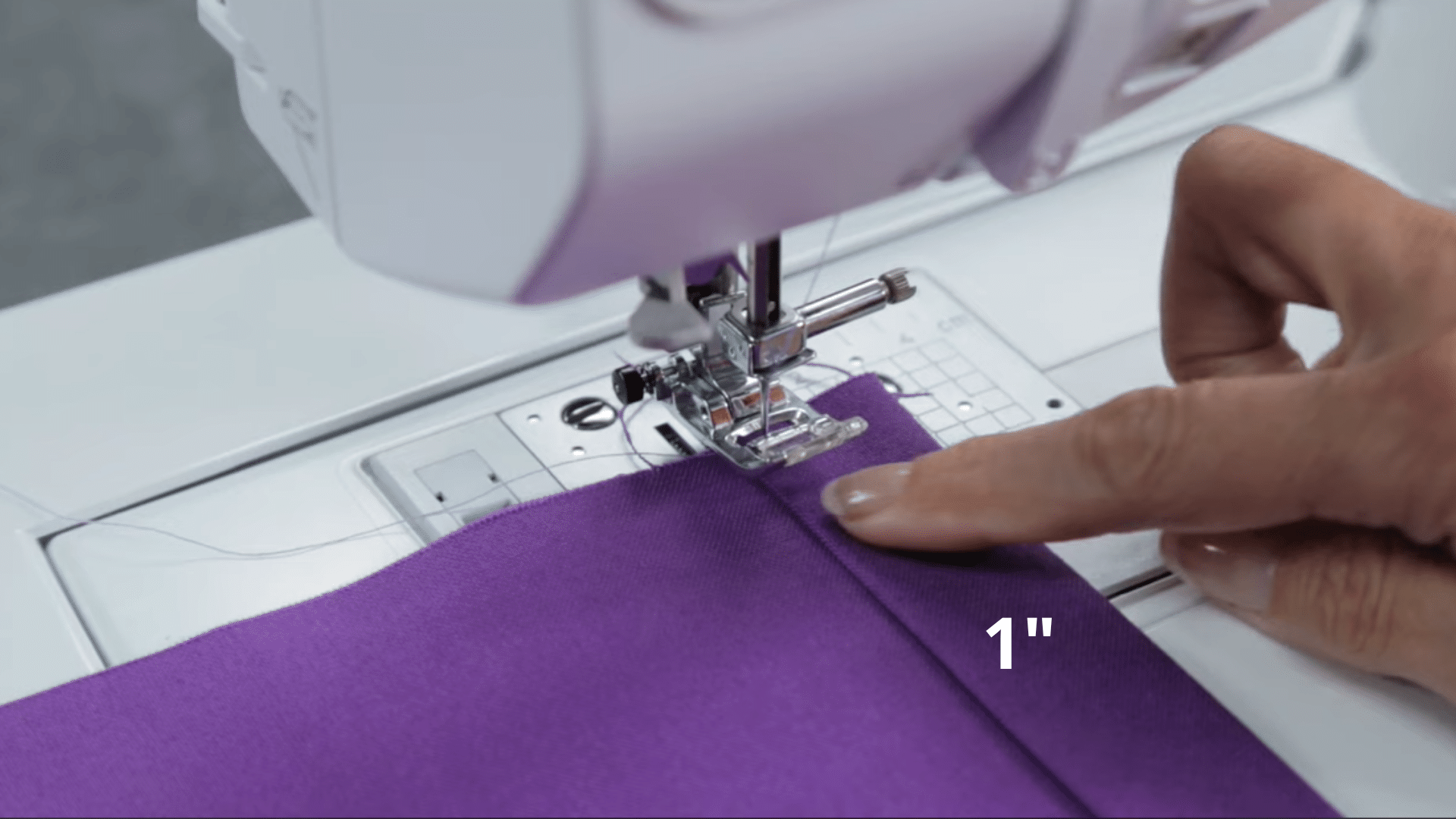 sewing machine stitching along folded fabric edge while guiding seam to create neat and even side hem for curtain panel