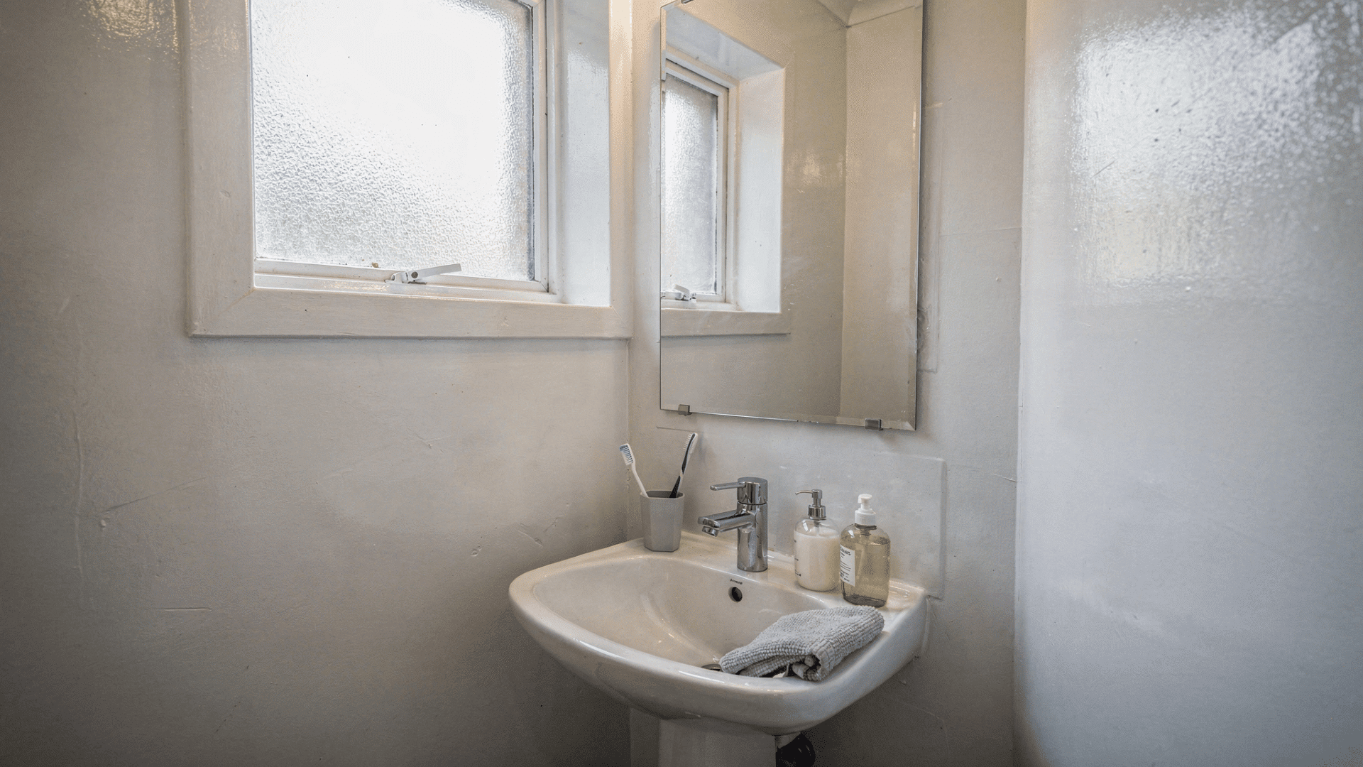 small white bathroom with semi gloss walls reflecting natural light from window making the space feel larger and brighter